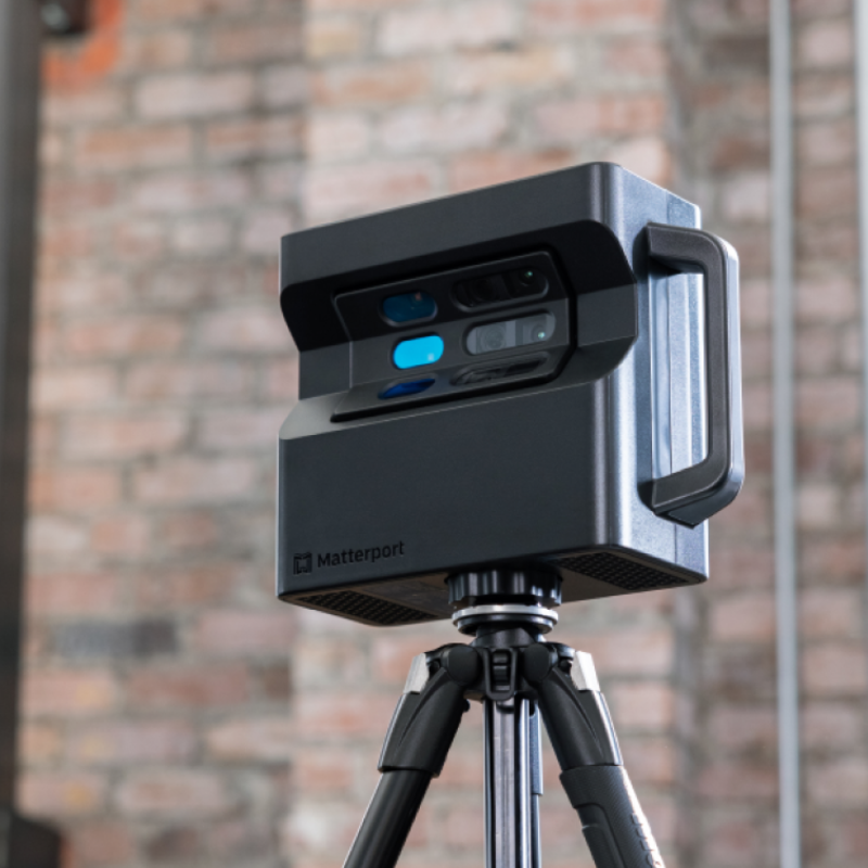 Uma câmera 3D Matterport montada em um tripé, com uma parede de tijolos ao fundo. a câmera possui várias lentes e um design elegante e moderno.
